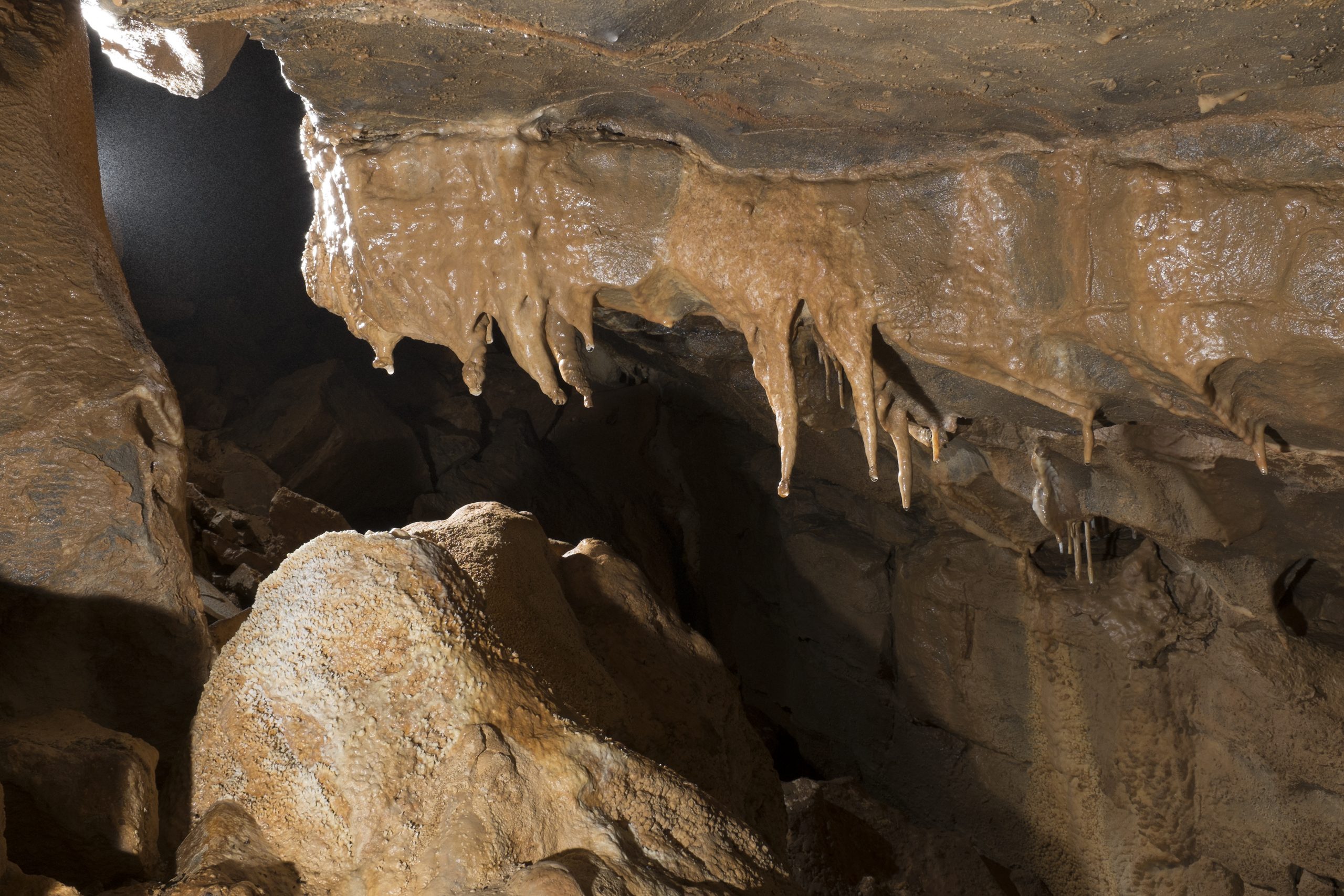 A tall, rift-like passage with ancient stal formations.